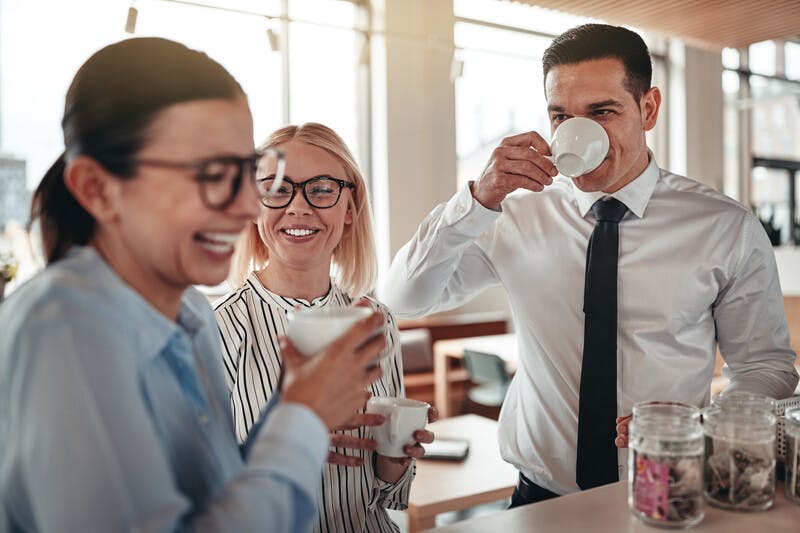 Young businesspeople laughing together during their office coffe