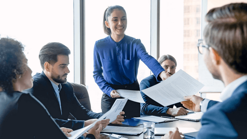 Smiling female employee share paperwork at meeting