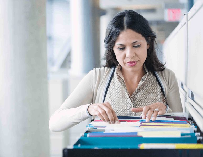 Businesswoman searching through a filing cabinet