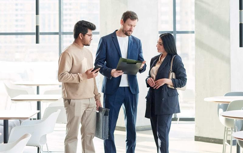 Minimal full length portrait of three business people talking in graphic white interior