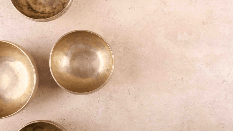 Tibetan singing bowls with sticks used during mantra meditations on beige stone background, top view, copy space