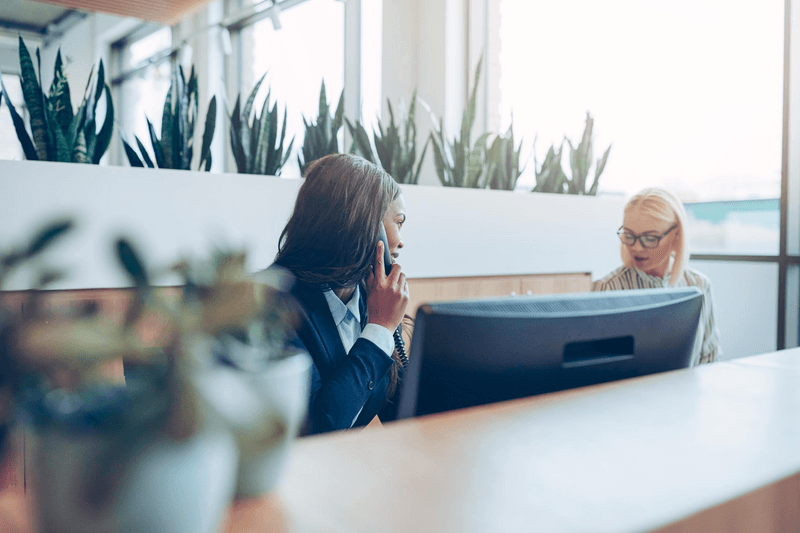 Two smiling diverse businesswomen working together at an office